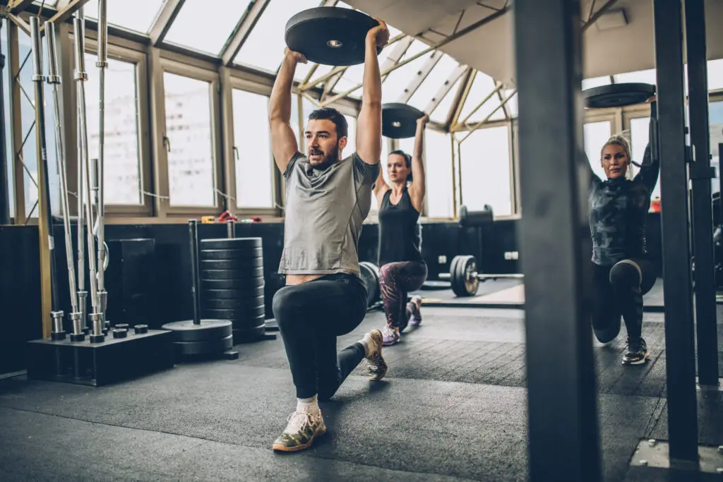 Three people, man fitness trainer and women in gym, instructor on lunge training as part of beginner strength training
