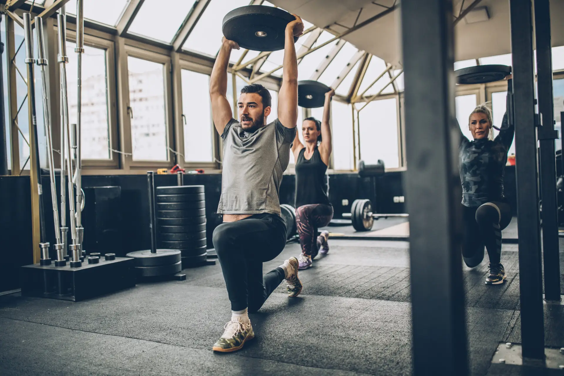Three people, man fitness trainer and women in gym, instructor on lunge training as part of beginner strength training