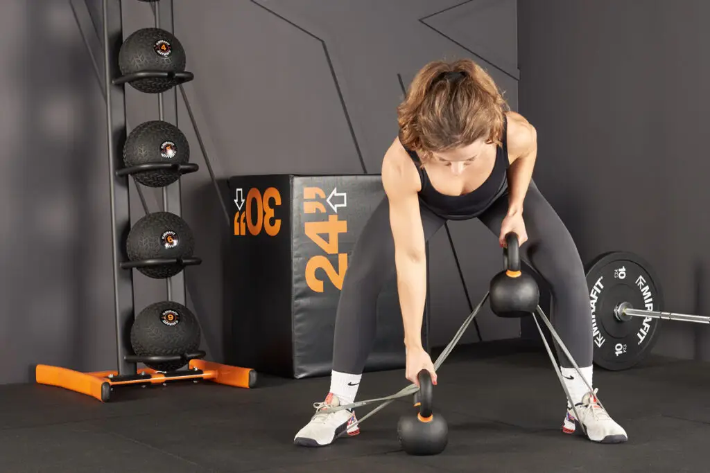 woman performing bent over rows with kettlebells and resistance bands