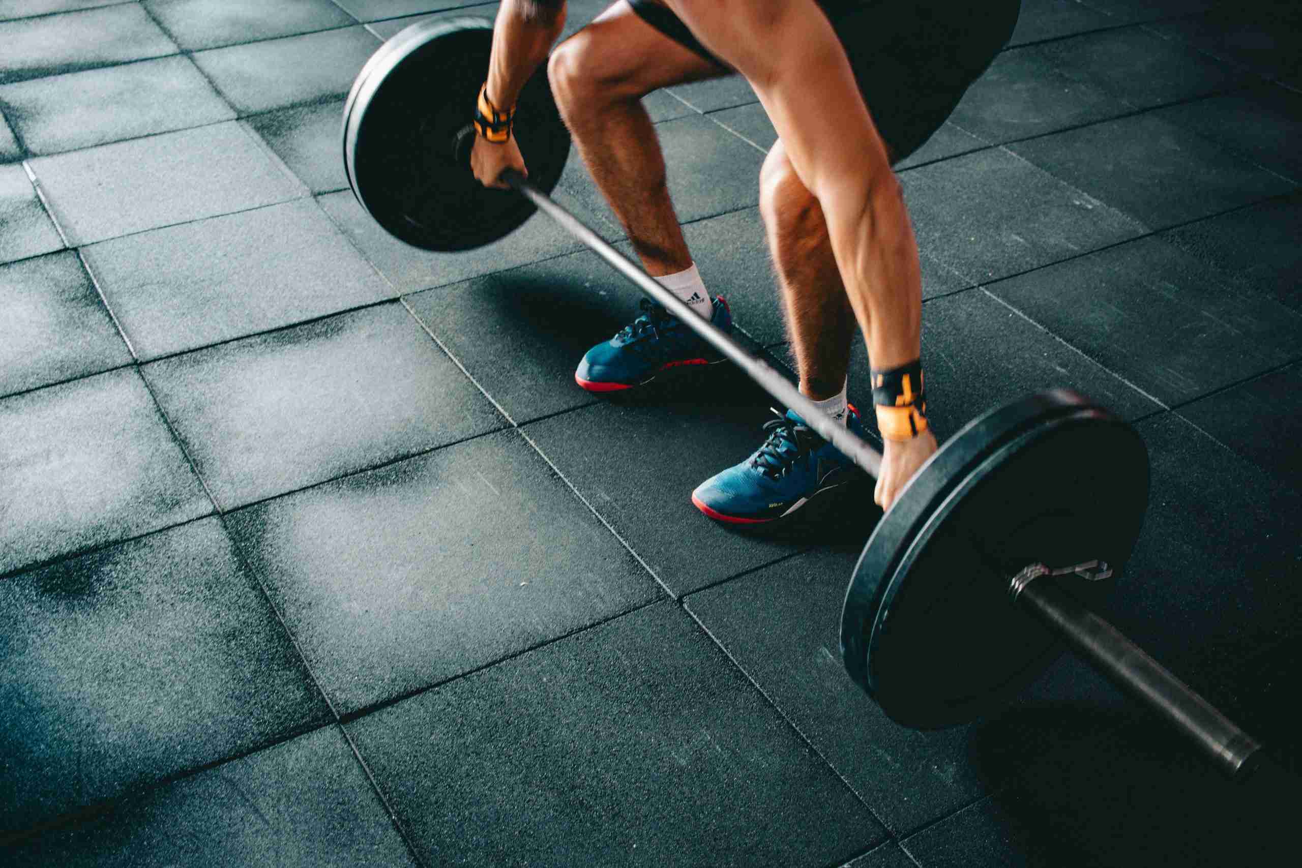 Runner performing strength exercises in gym, showing the connection between strength training and improved running performance.