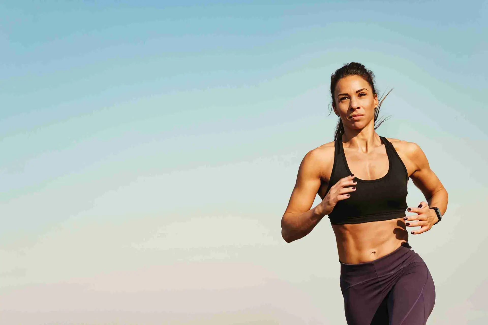 Hybrid athlete woman running outdoors – combining gym and running.