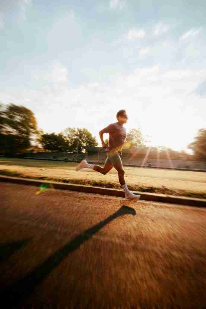 Runner exercising outdoors on track at sunset for cardio and weight loss