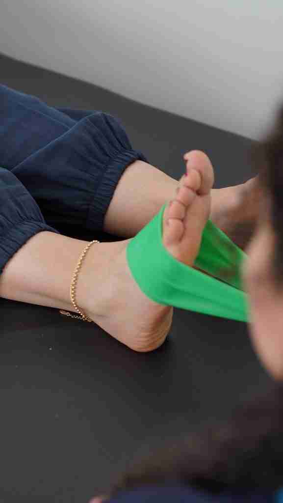 Close-up of a resistance band exercise targeting ankle and foot mobility during injury rehabilitation in an in-home personal training session for women
