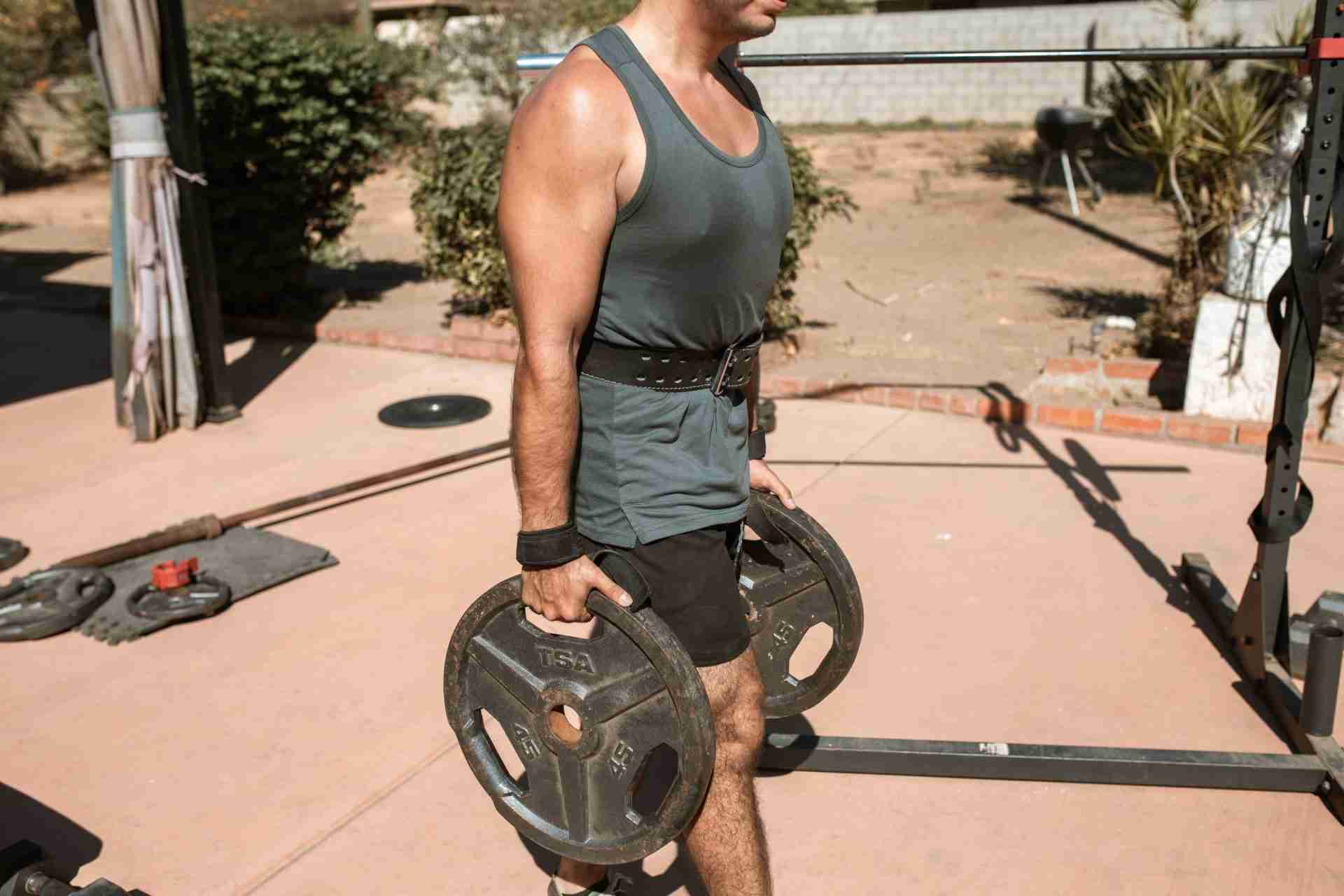 Man carrying weight plates during a farmer's carry exercise as functional strength training exercise