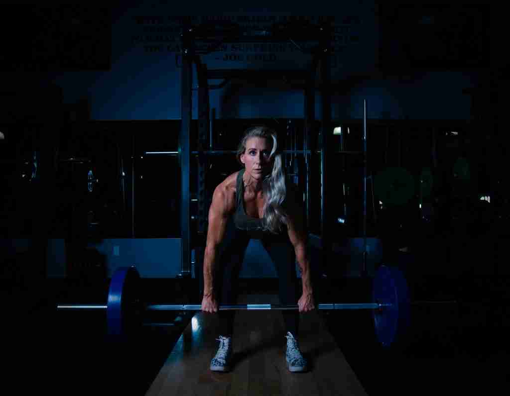 Woman lifting barbell in gym demonstrating strength training for muscle building