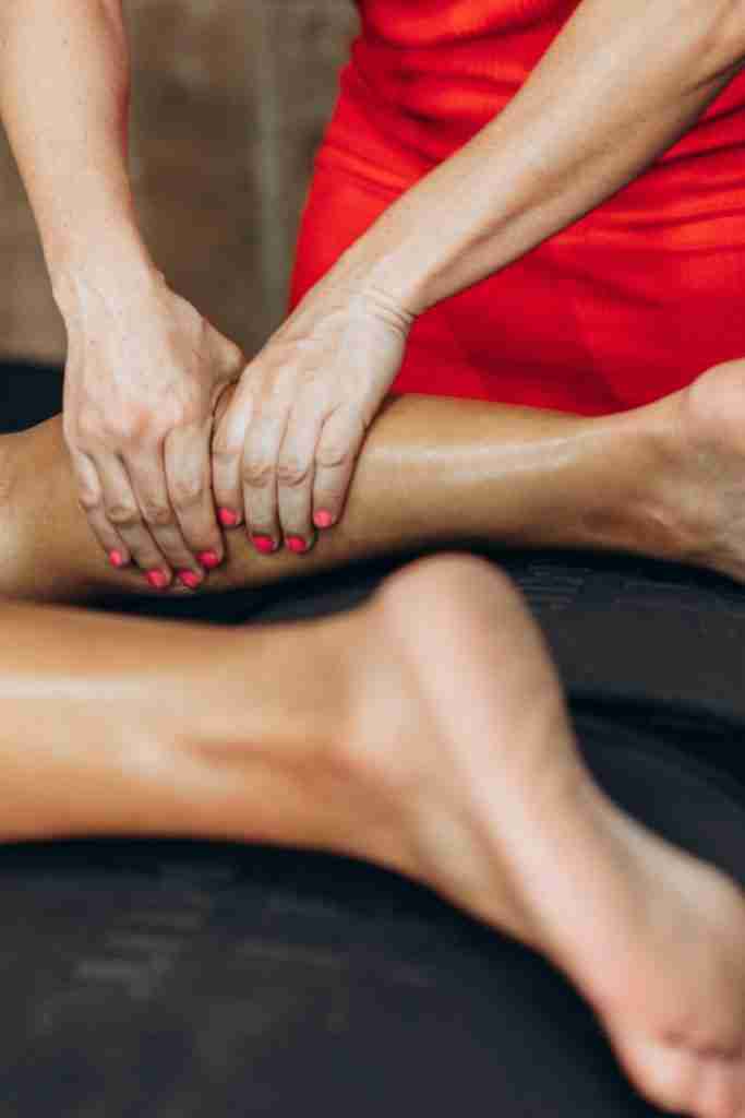 in-home personal trainer performing manual soft tissue therapy on a client's calf as part of injury rehabilitation