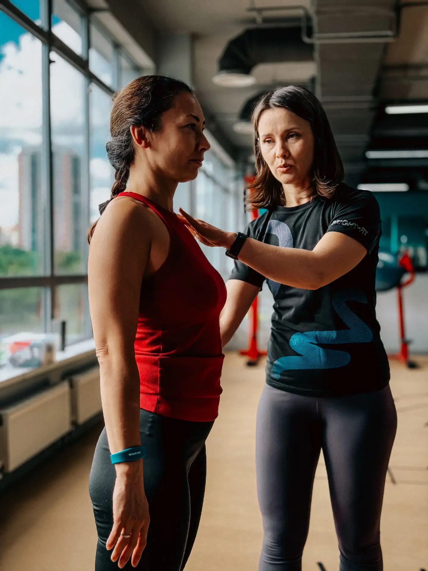 female personal trainer showing client how to perform exercise