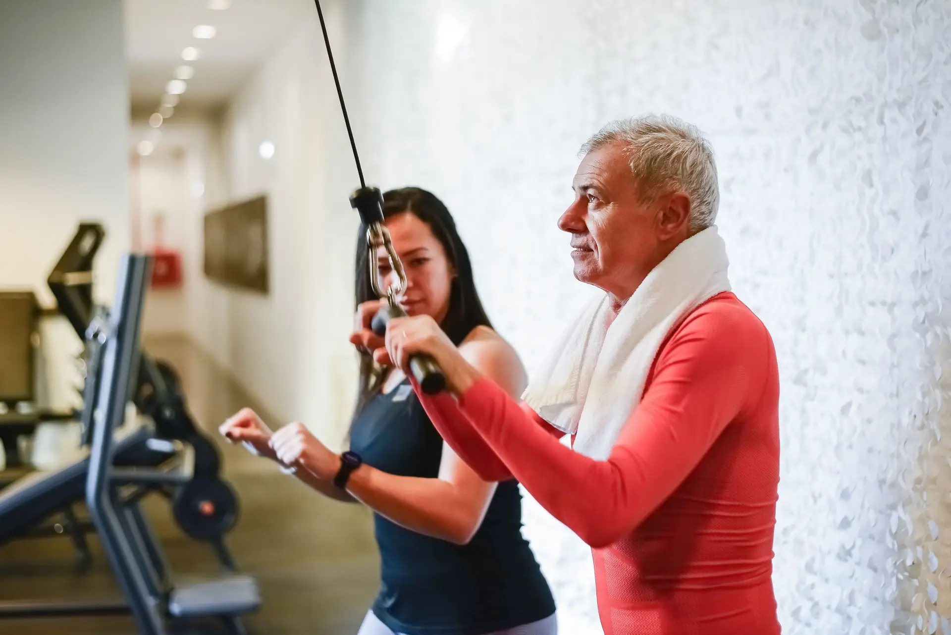 female personal trainer showing client a tricep extension exercise on cable machine in a condo gym